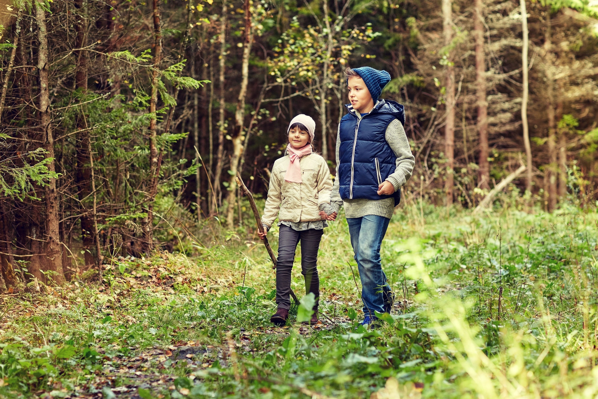 two happy kids walking along forest path