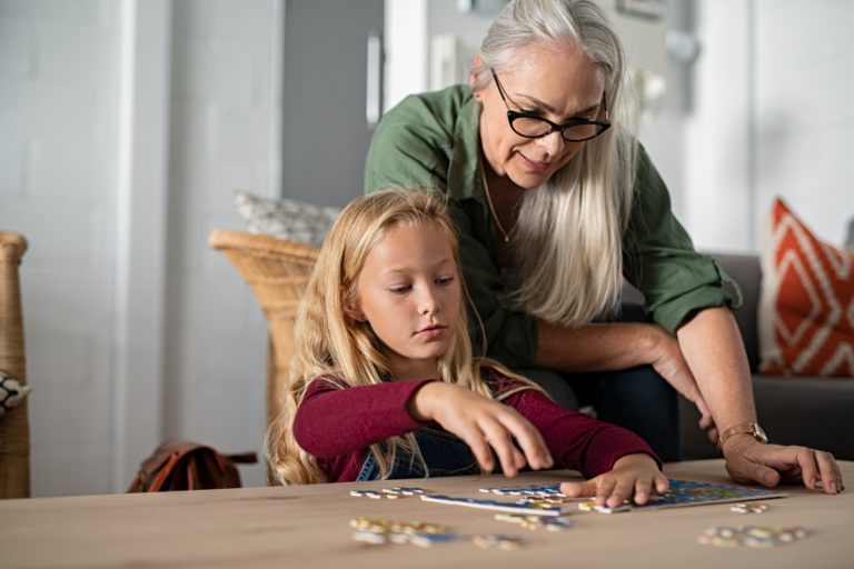Girl doing jigsaw puzzle with grandmother
