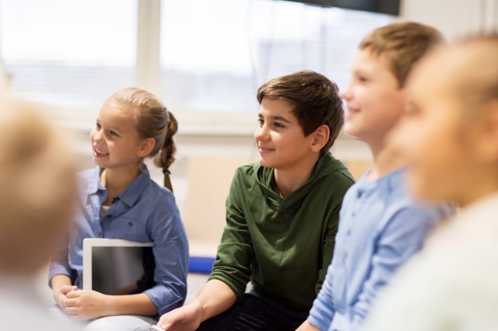 group of happy kids or friends learning at school