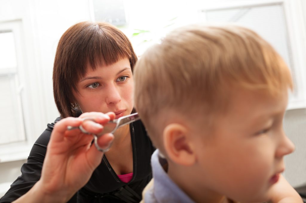 Hairdresser trimming a small boys hair